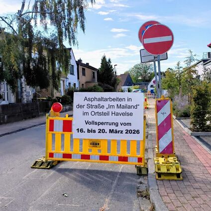 Baustelle mit Absperrung und Asphaltarbeiten im Straßenbereich